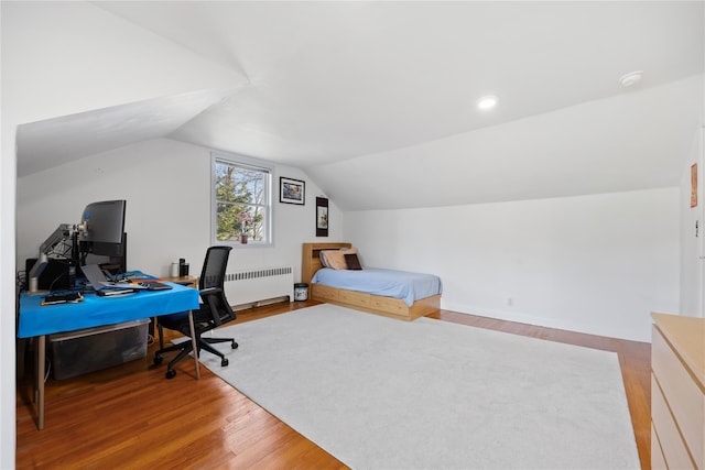 bedroom with radiator heating unit, wood-type flooring, and vaulted ceiling