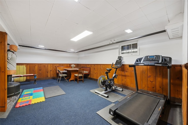 exercise room with carpet floors and wooden walls