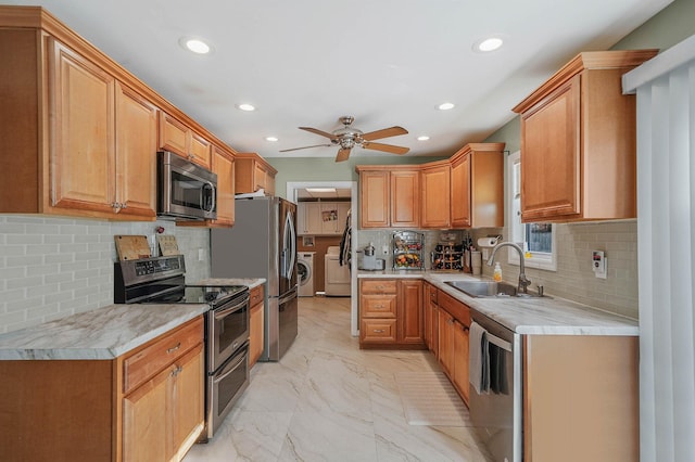 kitchen with sink, ceiling fan, backsplash, stainless steel appliances, and washing machine and dryer