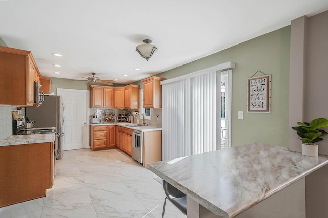 kitchen with tasteful backsplash, appliances with stainless steel finishes, sink, and ceiling fan