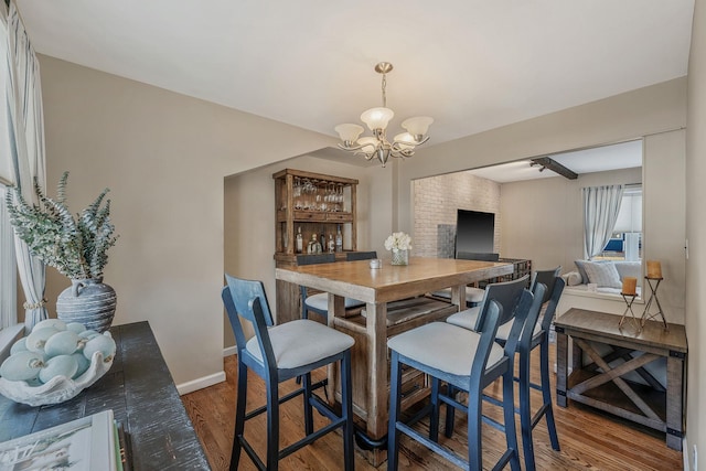 dining area with dark wood-type flooring and an inviting chandelier