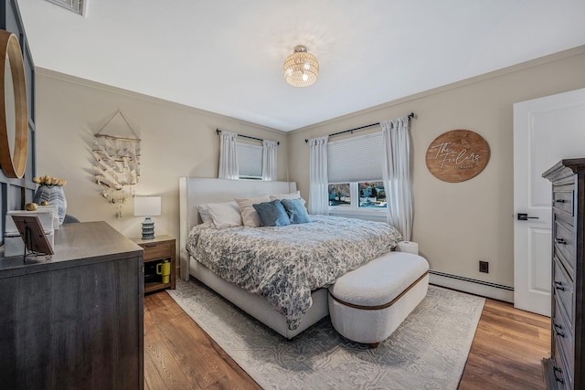 bedroom featuring hardwood / wood-style flooring, a baseboard radiator, and ornamental molding