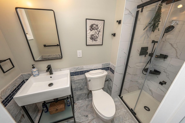 bathroom with toilet, an enclosed shower, sink, and tile walls