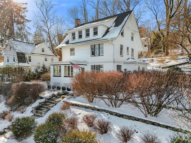 view of front facade with a sunroom and a chimney