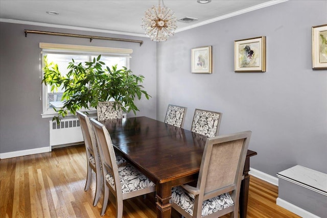 dining area with an inviting chandelier, hardwood / wood-style flooring, radiator heating unit, and ornamental molding