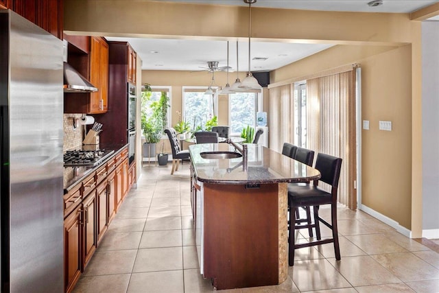 kitchen featuring sink, a breakfast bar, appliances with stainless steel finishes, a kitchen island with sink, and decorative light fixtures