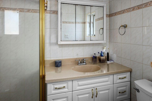 bathroom featuring vanity, tile walls, and toilet