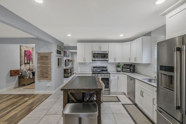 kitchen featuring sink, white cabinetry, light tile patterned floors, appliances with stainless steel finishes, and backsplash