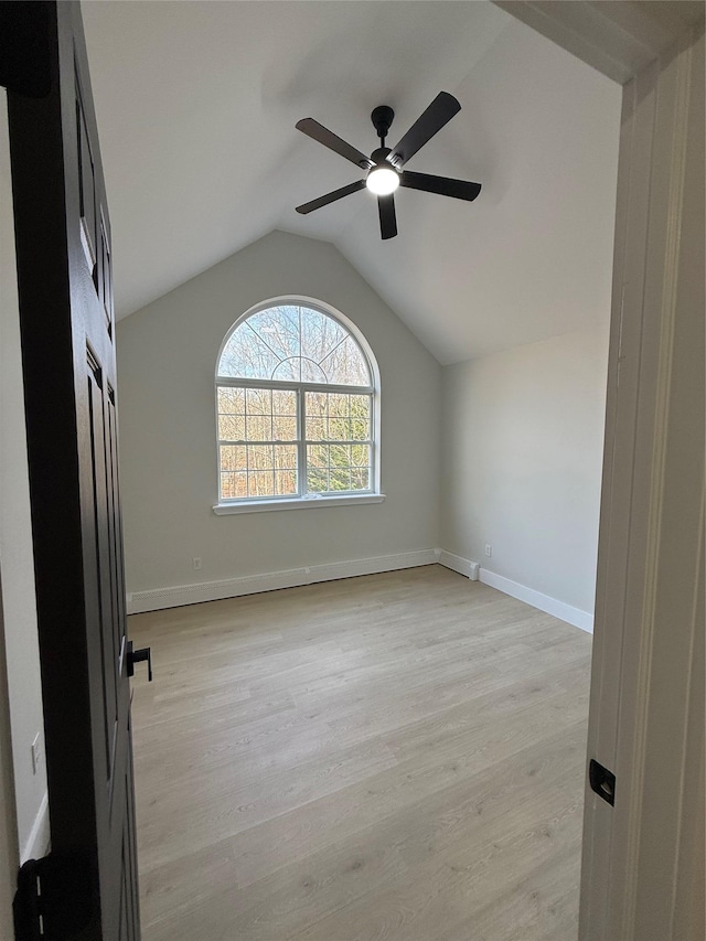 spare room with vaulted ceiling, ceiling fan, and light wood-type flooring