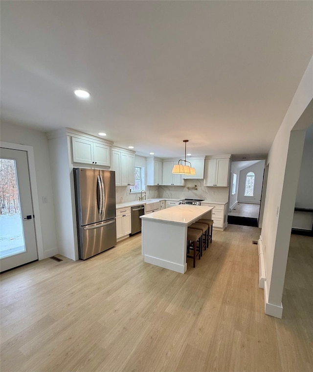 kitchen with pendant lighting, a breakfast bar, appliances with stainless steel finishes, a center island, and white cabinets