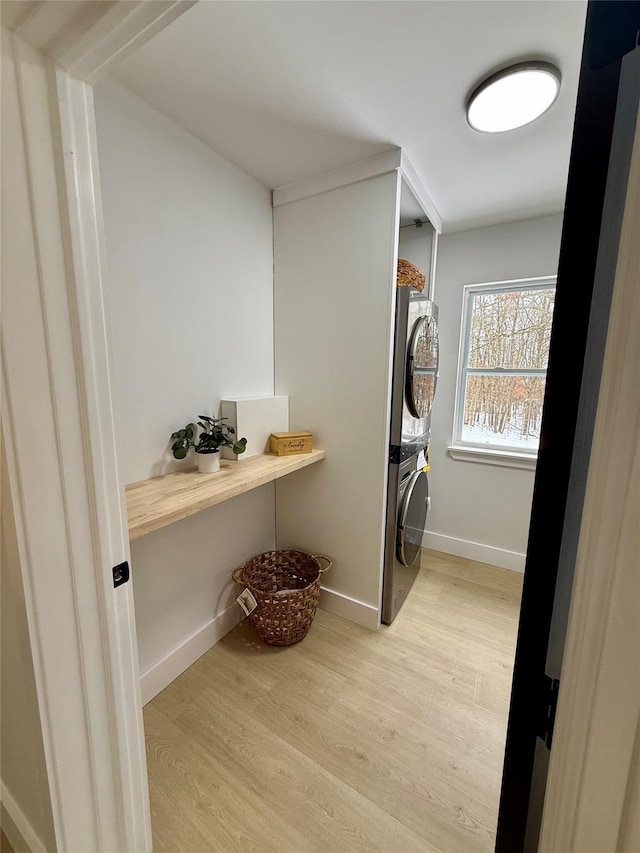 laundry area featuring stacked washer / drying machine and light hardwood / wood-style floors