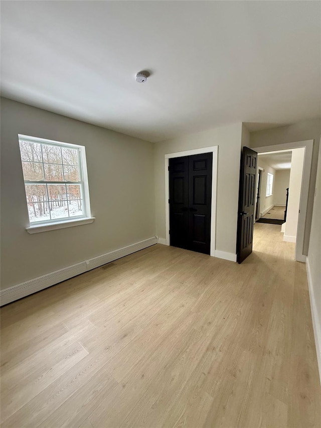 unfurnished bedroom featuring light hardwood / wood-style floors and baseboard heating