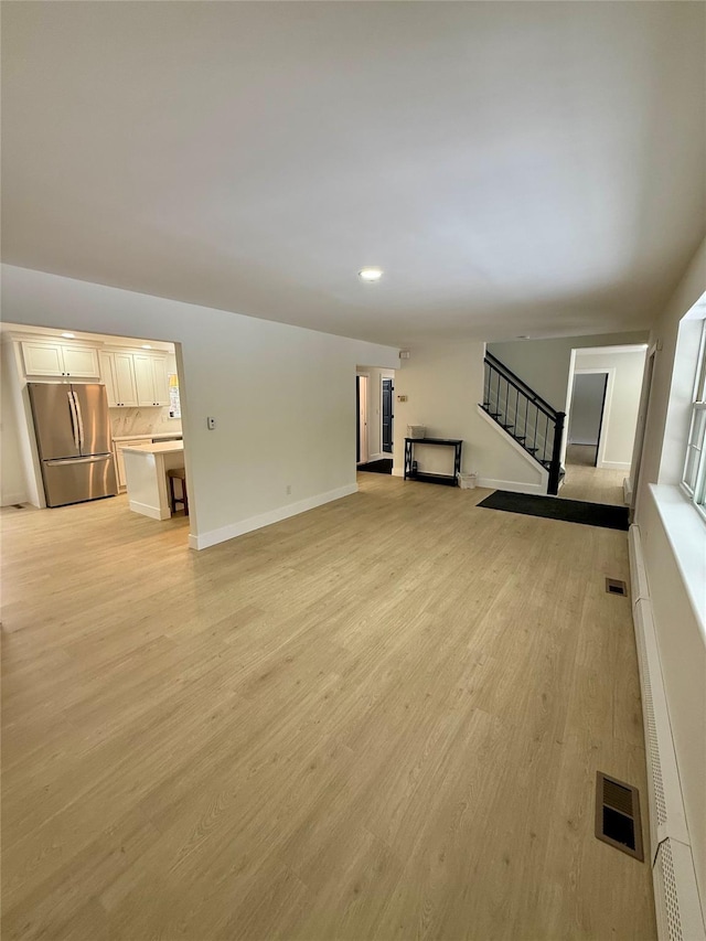 unfurnished living room with a baseboard heating unit and light hardwood / wood-style flooring