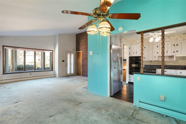 kitchen with dark colored carpet, stainless steel fridge, white cabinets, and a baseboard radiator