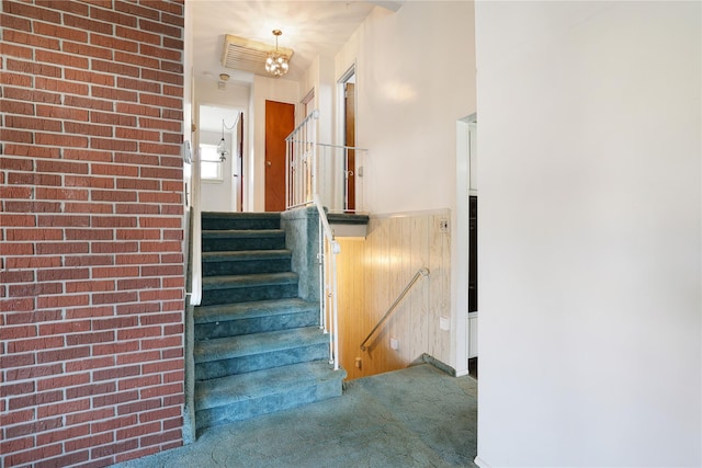 staircase with brick wall and carpet flooring