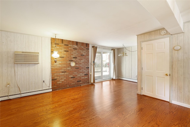 empty room with baseboard heating, a wall mounted air conditioner, a chandelier, and hardwood / wood-style flooring