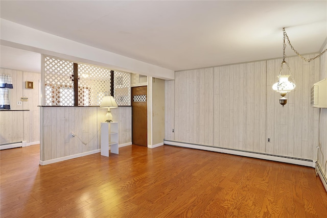 unfurnished living room with wood-type flooring, baseboard heating, and wood walls