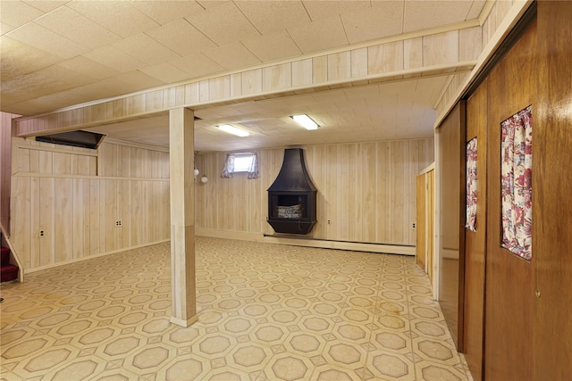 basement featuring a baseboard heating unit and wood walls