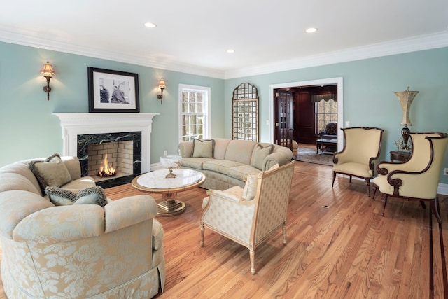 living area featuring light wood-type flooring, a premium fireplace, crown molding, and recessed lighting