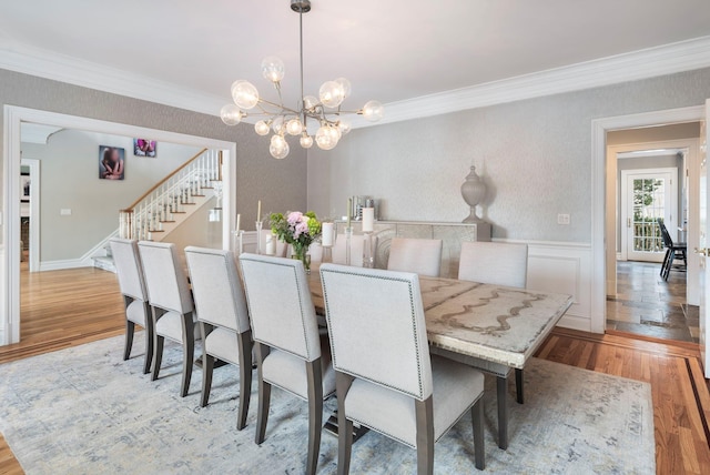 dining room with light wood-type flooring, a wainscoted wall, crown molding, and stairway