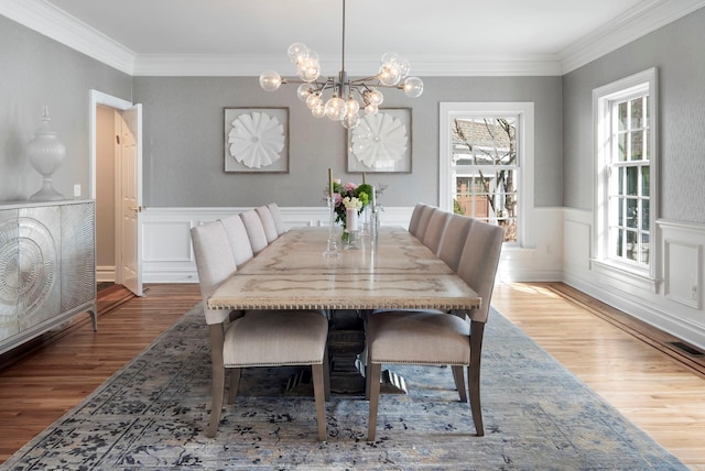 dining space featuring crown molding, visible vents, wood finished floors, and wainscoting