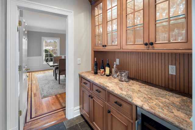 bar featuring a dry bar, beverage cooler, dark wood finished floors, wainscoting, and crown molding