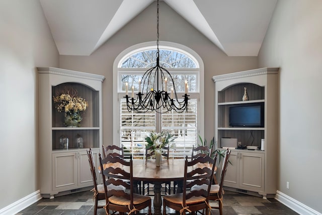 dining space with lofted ceiling, baseboards, stone finish floor, and a notable chandelier