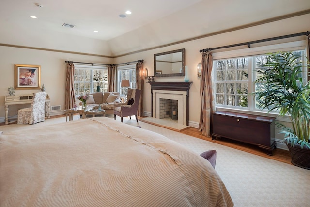 bedroom with a fireplace with raised hearth, lofted ceiling, visible vents, and baseboards