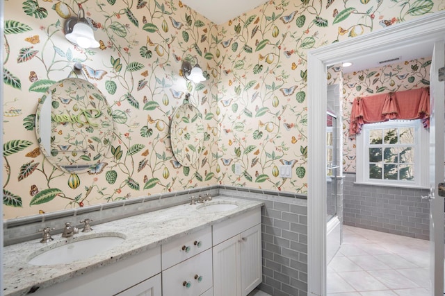 bathroom featuring a wainscoted wall, double vanity, a sink, and wallpapered walls