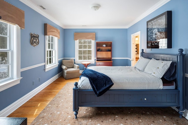 bedroom with visible vents, crown molding, baseboards, and wood finished floors