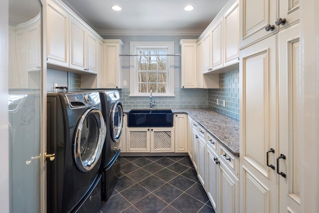 clothes washing area featuring dark tile patterned flooring, a sink, washer and dryer, cabinet space, and crown molding