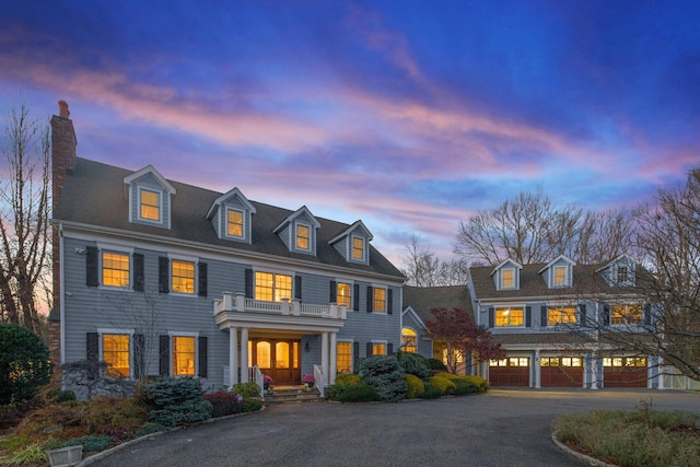 colonial house with a balcony, a garage, and aphalt driveway