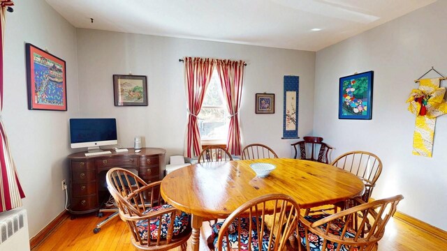 dining room with light wood-style flooring, radiator heating unit, and baseboards