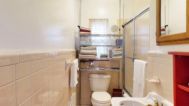 full bath with toilet, tile walls, and a stall shower