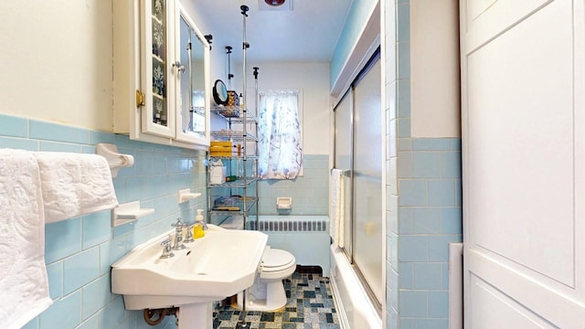 full bath featuring radiator, toilet, tile walls, and a sink