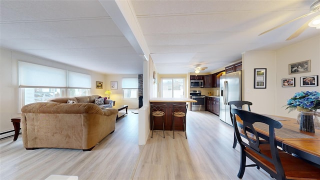 living area featuring ceiling fan, a baseboard radiator, and light wood-style flooring