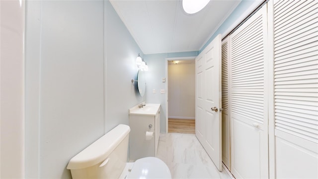 half bath featuring a closet, marble finish floor, toilet, and vanity