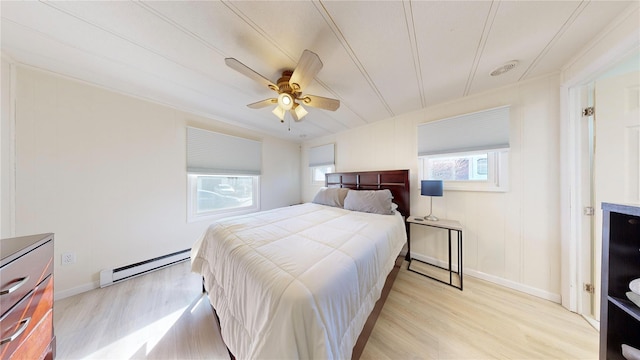 bedroom featuring light wood finished floors, a ceiling fan, baseboards, and baseboard heating