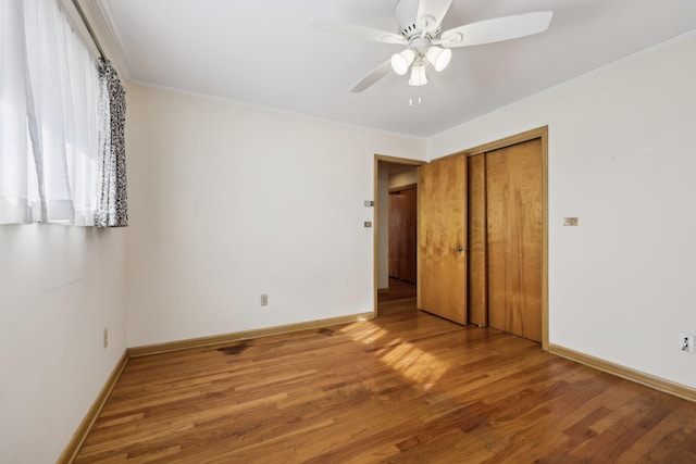 unfurnished bedroom with hardwood / wood-style flooring, ceiling fan, ornamental molding, and a closet