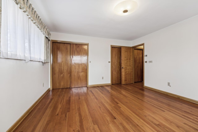 unfurnished bedroom with multiple closets and hardwood / wood-style floors