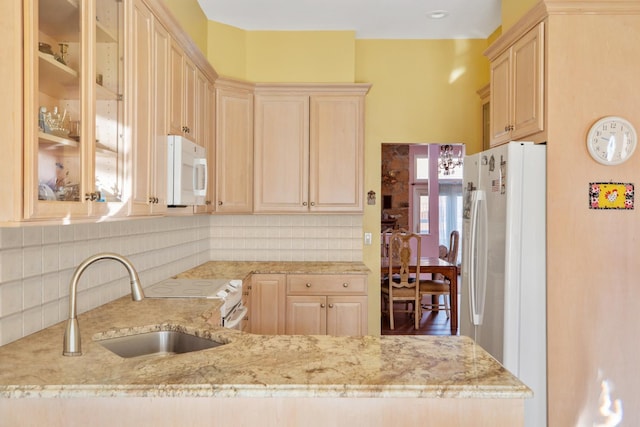 kitchen featuring sink, white appliances, backsplash, light stone counters, and kitchen peninsula