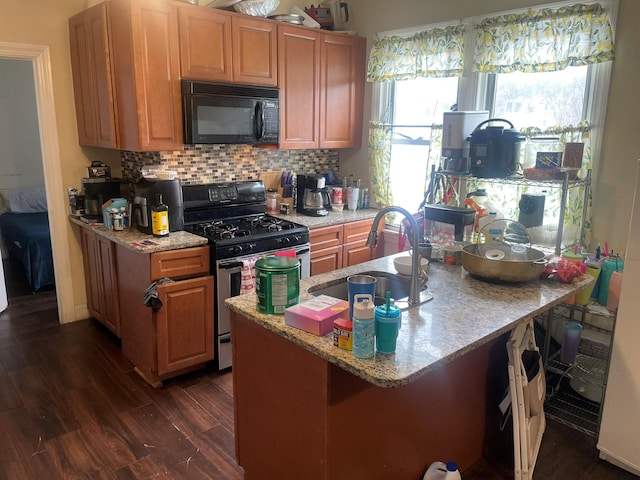 kitchen with sink, stainless steel gas range, backsplash, light stone counters, and dark hardwood / wood-style flooring