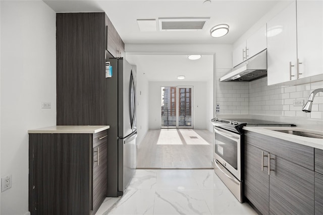 kitchen featuring sink, white cabinets, decorative backsplash, dark brown cabinetry, and stainless steel appliances