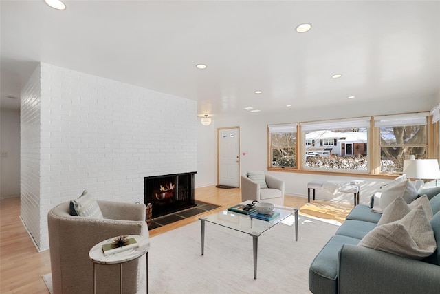 living room with a brick fireplace and light wood-type flooring