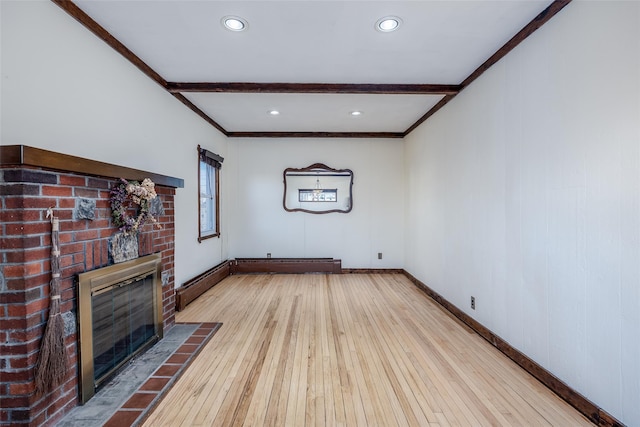 unfurnished living room featuring beamed ceiling, ornamental molding, a brick fireplace, and light hardwood / wood-style floors