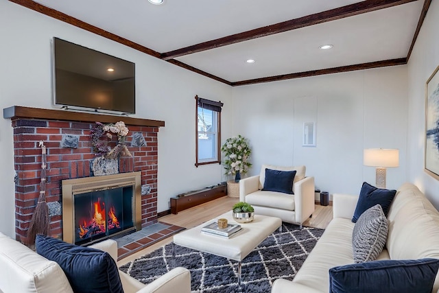 living room with beamed ceiling, crown molding, a brick fireplace, and light hardwood / wood-style floors