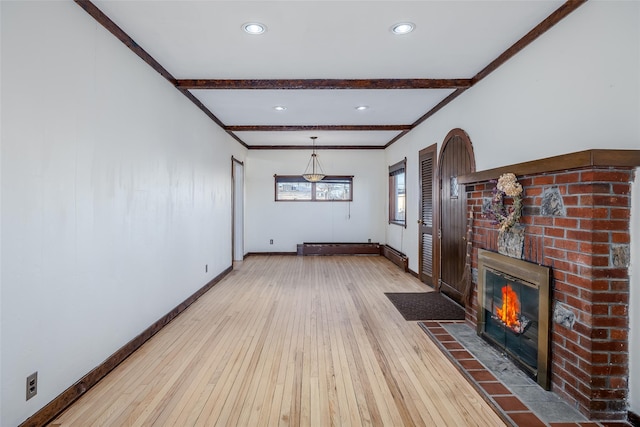 unfurnished living room with hardwood / wood-style flooring, ornamental molding, a fireplace, and beamed ceiling