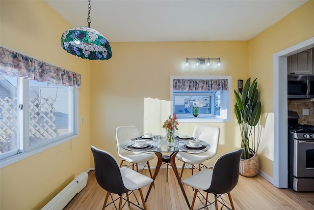 dining area with a baseboard heating unit and light hardwood / wood-style floors