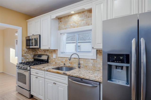 kitchen featuring light stone countertops, white cabinetry, appliances with stainless steel finishes, and sink