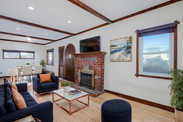 living room with beamed ceiling, a healthy amount of sunlight, and light wood-type flooring